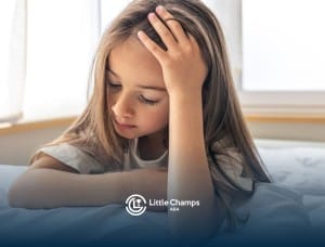 Young child with autism resting her head on her arm, looking thoughtful or upset indoors.