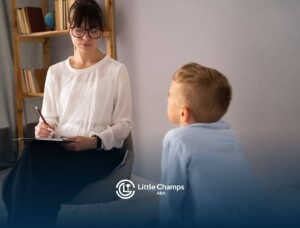 BCBA taking notes while speaking with a young boy in ABA therapy.