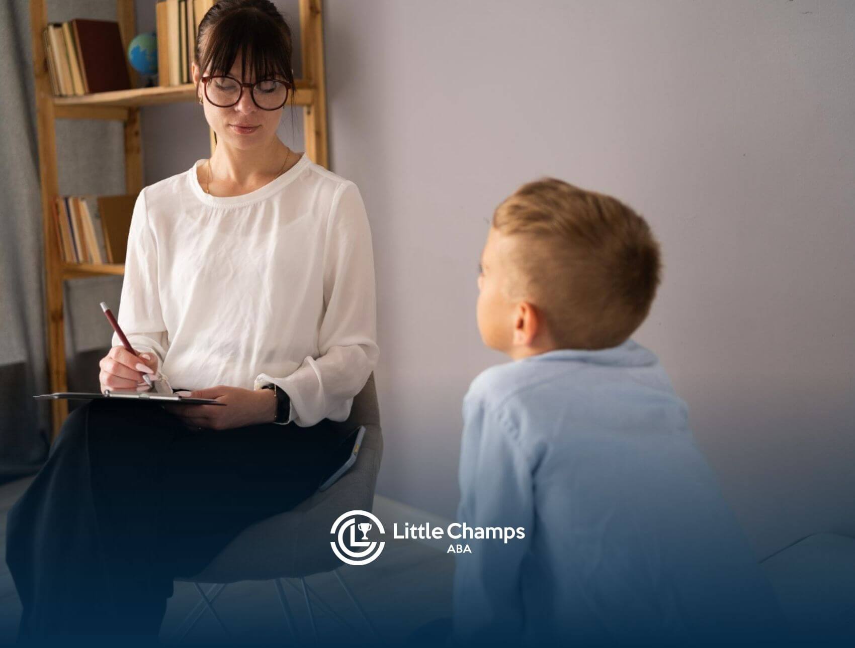 BCBA taking notes while speaking with a young boy in ABA therapy.