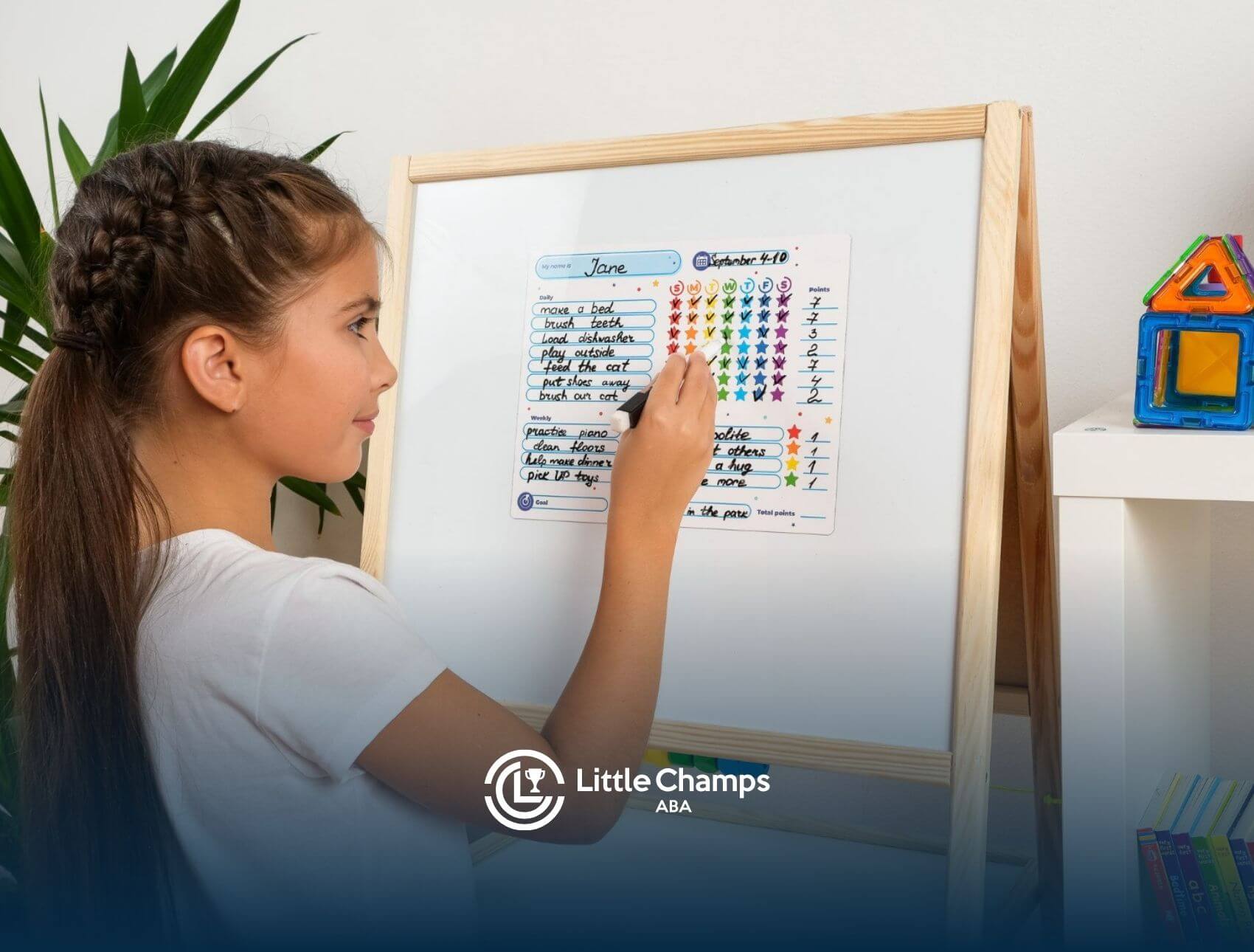 A young girl with autism using a marker to fill out a colorful daily chore on an easel.