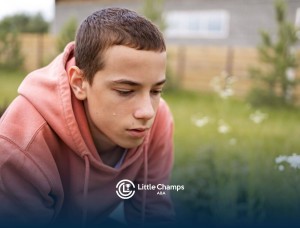 Teenager with autism looking down with a sad expression in a garden.