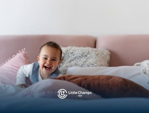 Happy baby with autism playing on a bed with soft pillows.