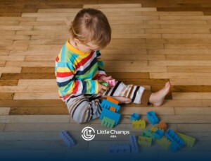 Young child playing with colorful blocks on floor.