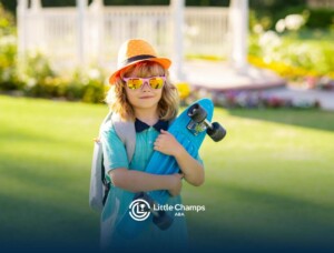 A child with autism in an orange fedora and pink sunglasses holding a blue skateboard.