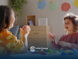 A BCBA and a young autistic child clap hands while playing with colorful shapes at a table.