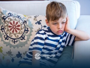 Young boy with a worried expression sitting on a couch.