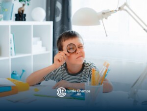Young boy with autism using a magnifying glass during a learning activity at his desk.