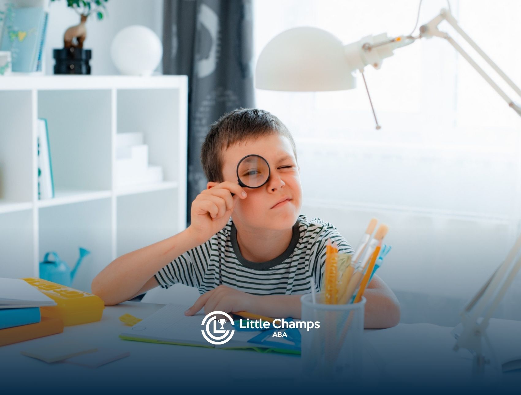 Young boy with autism using a magnifying glass during a learning activity at his desk.